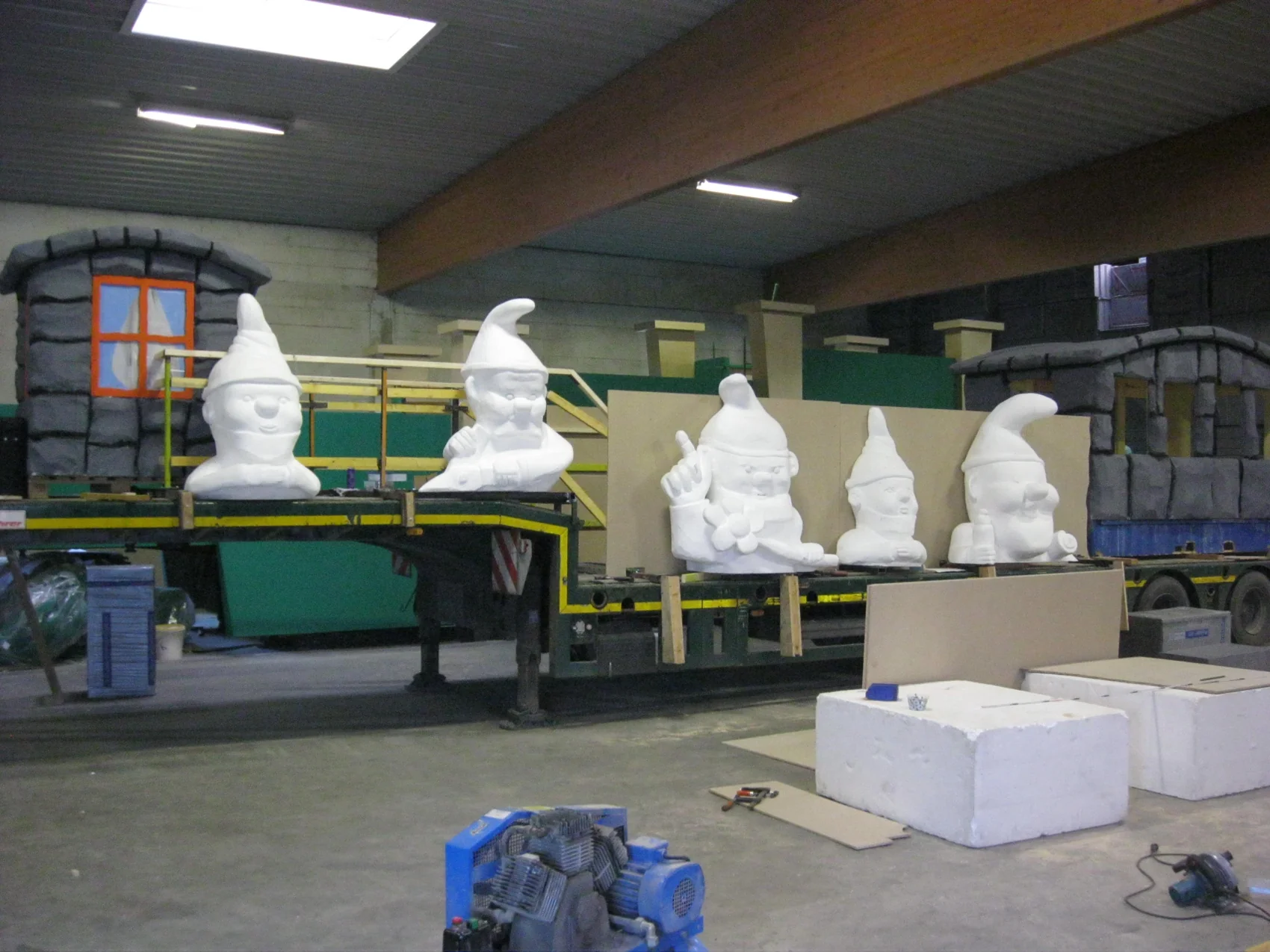 Mehrere weiße Gartenzwerg-Figuren in verschiedenen Größen warten in der Werkstatt